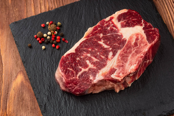 Fresh raw Prime Black Angus beef steaks on stone board: Striploin, Rib Eye. Top view. On a dark wood background - Fotoğraf, Görsel