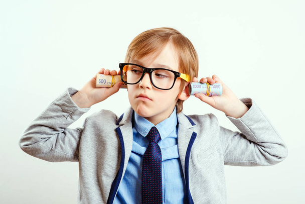 Financial education for children. Smart boy with rolls of money. Little successful businessman on white. Financial monitoring of currency. Future profession. Little boss in eyeglasses and suit. - Photo, Image