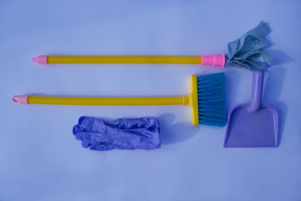 Cleaning tools. Broom, marking on the handle, scoop, gloves. View from above on a blue background. - Zdjęcie, obraz