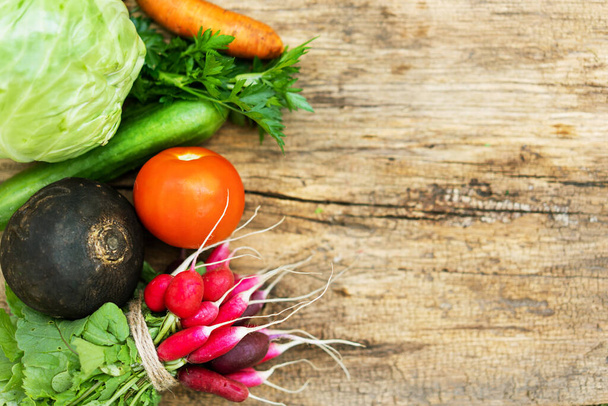 Exposition of fresh organic vegetables on woodetable. Tomatoes, cabbage, radish, cucumber, parsley, black radish, carrot - Photo, image