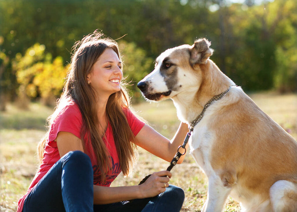 girl with her Central asian shepherd dog in autumn sunny park - Foto, imagen