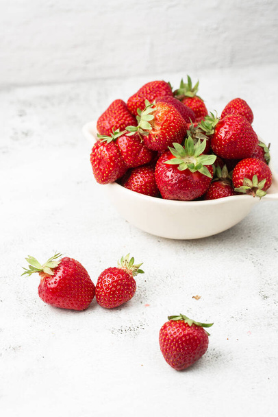 Fresh strawberries in a bowl on marble black table. Fresh nice strawberries. Juice strawberry. Strawberry field on fruit farm. Fresh ripe organic strawberry in white basket next to strawberries bed on pick your own berry plantation. - Photo, image