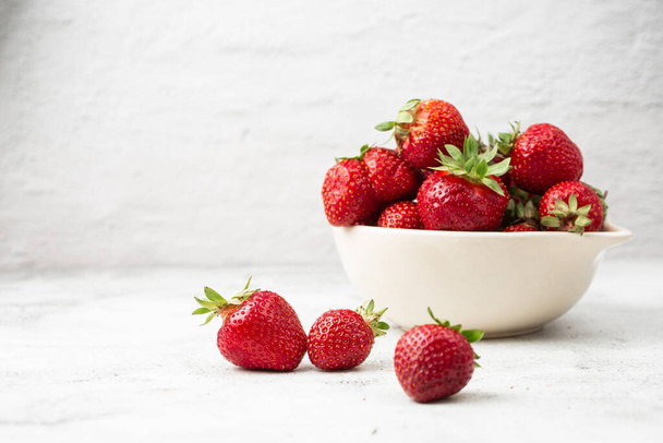 Fresh strawberries in a bowl on marble black table. Fresh nice strawberries. Juice strawberry. Strawberry field on fruit farm. Fresh ripe organic strawberry in white basket next to strawberries bed on pick your own berry plantation. - Foto, imagen