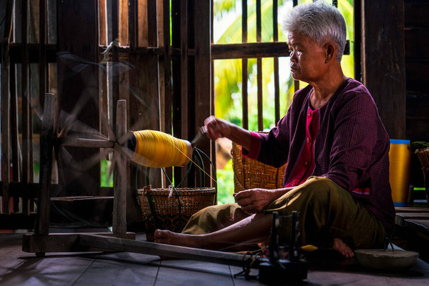 タイシルクの職人。地元の教師のマスターは、元の絹の織物は、ブリラム州のコミュニティです。タイの老婦人は、紡糸天然カラフルな糸や糸を示す. - 写真・画像