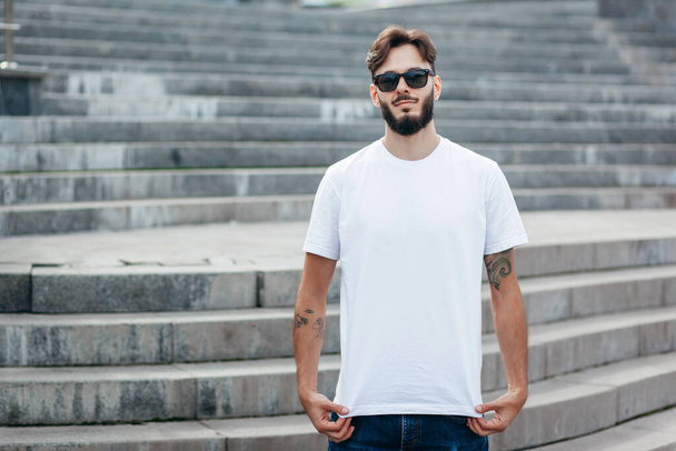 Mladý stylový muž s vousy v bílém tričku a brýlích. Fotografie z ulice - Fotografie, Obrázek