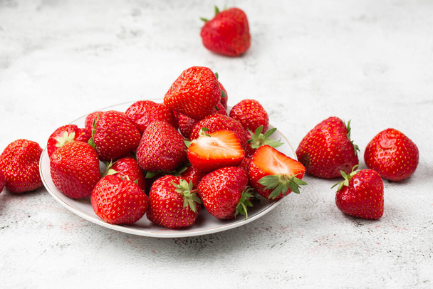 Fresh strawberries in a bowl on marble black table. Fresh nice strawberries. Juice strawberry. Strawberry field on fruit farm. Fresh ripe organic strawberry in white basket next to strawberries bed on pick your own berry plantation. - Photo, Image