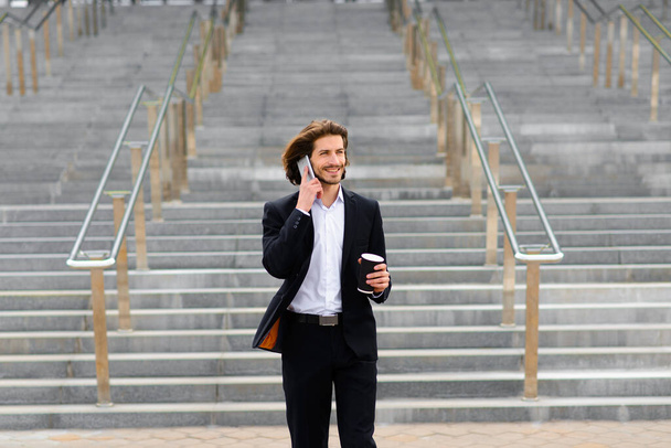 Porträt eines gutaussehenden Geschäftsmannes mit Telefon, Kaffeetasse in den Straßen der Stadt - Foto, Bild