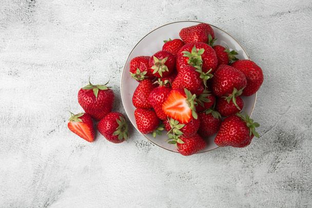 Fresh strawberries in a bowl on marble black table. Fresh nice strawberries. Juice strawberry. Strawberry field on fruit farm. Fresh ripe organic strawberry in white basket next to strawberries bed on pick your own berry plantation. - Photo, Image