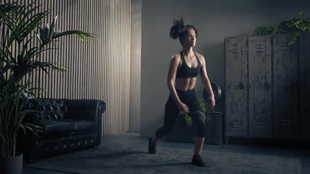 Woman exercising at home.Woman doing fitness legs training at home. Woman jumping lunges. Industrial style house. Bodycare,determination. Static tripod shot - Metraje, vídeo