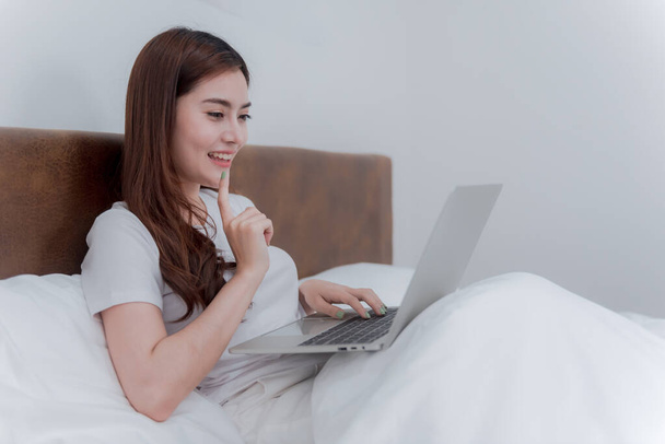 Ázsiai gyönyörű nő Használja laptop Keresés az interneten Mosolygott, és boldog volt. A hálószobában. - Fotó, kép