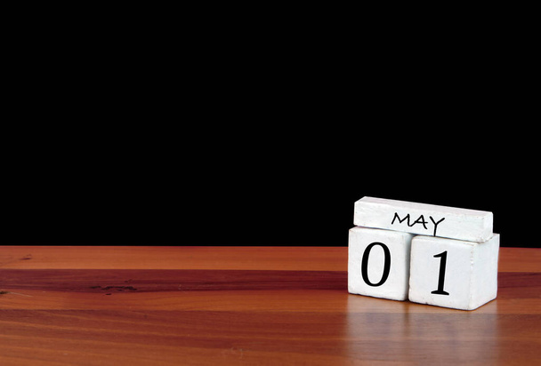 1η Μαΐου ημερολογιακού μήνα. 1 ημέρα του μήνα. Ανακλαστικό ημερολόγιο σε ξύλινο πάτωμα με μαύρο φόντο - Φωτογραφία, εικόνα