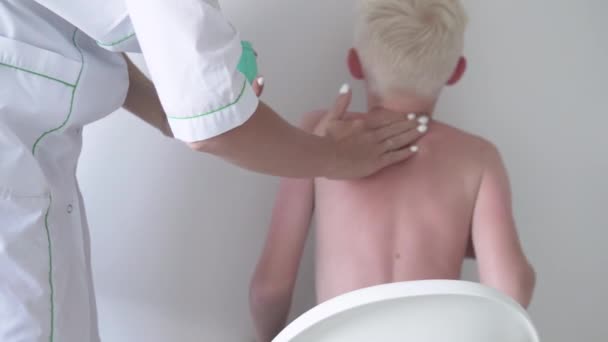The doctor applies moisturizing aloe lotion to the charred skin of an albino boy. - Footage, Video