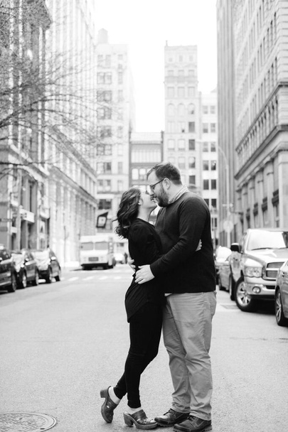 Bir adam ve bir kadın şehir ortamında el ele tutuşup öpüşüyorlar. - Fotoğraf, Görsel