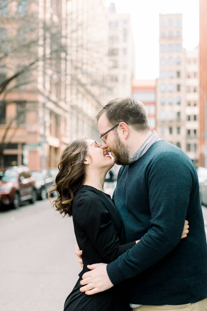 Egy férfi és egy nő kéz a kézben csókolóznak egy városi környezetben. - Fotó, kép