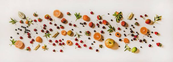 Fresh summer fruit and berries variety layout. Flay-lay of peaches, apricots, cherries, strawberries, blueberries, oranges and limes over plain white background, top view - Foto, afbeelding