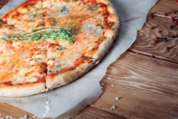 Appetizing pizza on a wooden table surrounded by herbs and spices. The concept of delicious food, restaurants and cafes - Photo, image
