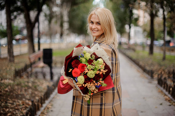 smiling blonde woman with bright flower bouquet in her hands - Fotó, kép