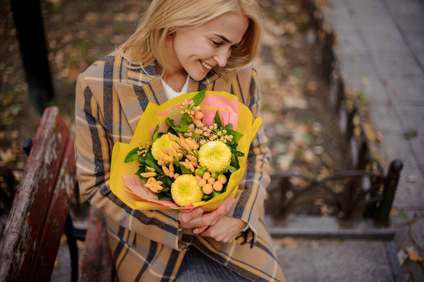 woman neatly holds in her hands bouquet of yellow flowers - Foto, Imagem