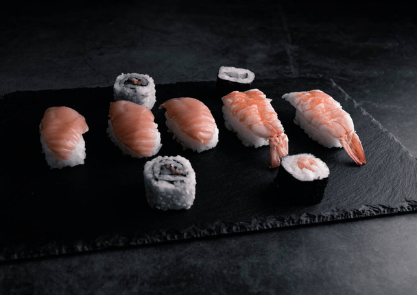 Sushi kootaan wasabilla ja inkiväärillä mustalla kivialustalla mustalla pöydällä. Yläkuva. - Valokuva, kuva