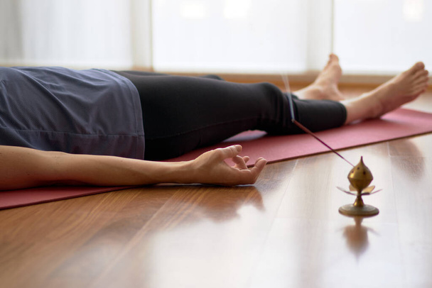 femme pratiquant le yoga, couché dans la pose de nidra de yoga, exercice dans Shavasana, exercices, travail, repos après la pratique, main féminine. Concept de mode de vie sain - Photo, image