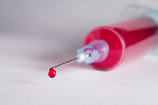 Drop of blood dripping from syringe after extracting it from patient - Valokuva, kuva