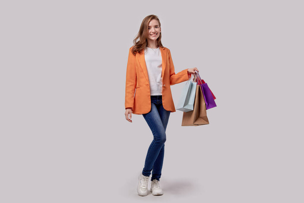 Dívka v neformálním oblečení drží v ruce nákupy v balíčcích. Radostná tvář. - Fotografie, Obrázek