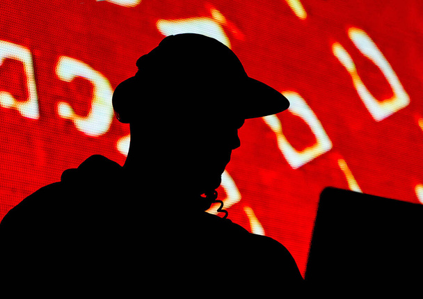 DJ, silueta muže v čepici a sluchátka izolované na červeném pozadí - Fotografie, Obrázek
