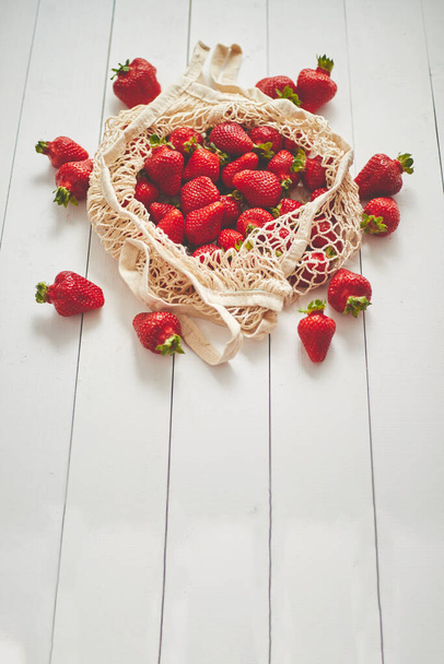 Frische Erdbeeren in umweltfreundlicher Verpackung auf weißem Holzhintergrund. Vegetarische Bio-Mahlzeit - Foto, Bild