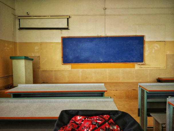 Μια αίθουσα διδασκαλίας με μπλε πίνακα, παγκάκια, εγκατάσταση προβολέα, κάμερα και μια σχολική τσάντα. Αυτή είναι η τάξη του κολεγίου μου. - Φωτογραφία, εικόνα