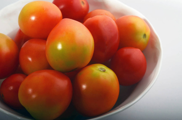 Rote, saftige Tomaten isoliert in einer weißen runden Schüssel - Foto, Bild