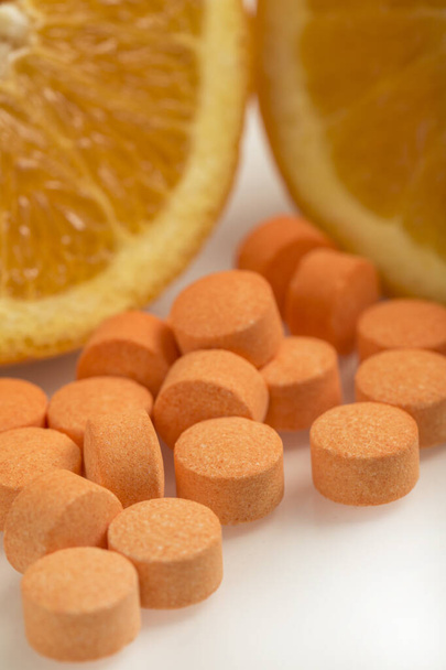 Pastillas de vitamina C con fruta naranja sobre fondo blanco. Concepto de salud
 - Foto, imagen