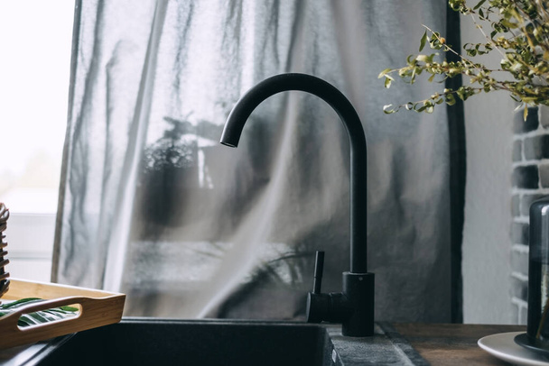 Black faucet or water tap with metal washing sink in the kitchen. High quality photo - Foto, Imagem