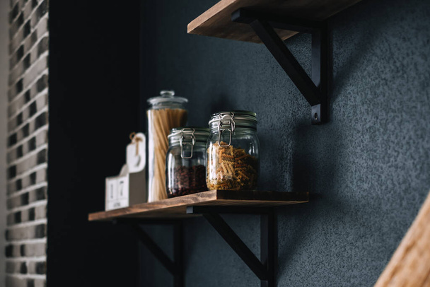 Těstoviny a potraviny ve skleněných nádobách na dřevěné polici v kuchyni. Detail. Kvalitní fotografie - Fotografie, Obrázek
