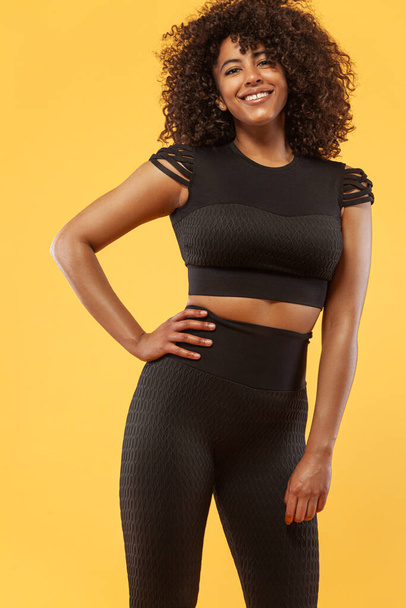 Lifestyle Concept. Portrait of beautiful African American woman with curly hair joyful listening to music on mobile phone. Yellow studio background. Copy Space. - Zdjęcie, obraz