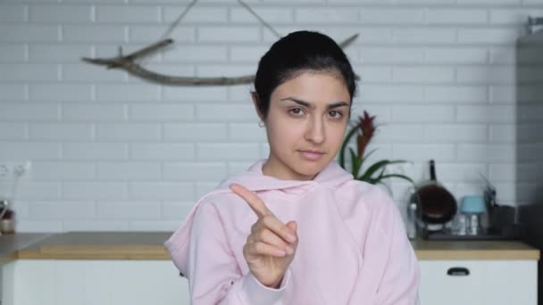 Una giovane donna indiana sta in una cucina luminosa e punta il dito No No No - Filmati, video