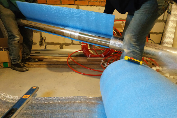 lavoratori avvolgere tubo zincato con lamina di metallo nella casa di nuova costruzione. Misurare la lunghezza e la larghezza del foglio, avvolgerlo e nastro adesivo. 2020 - Foto, immagini