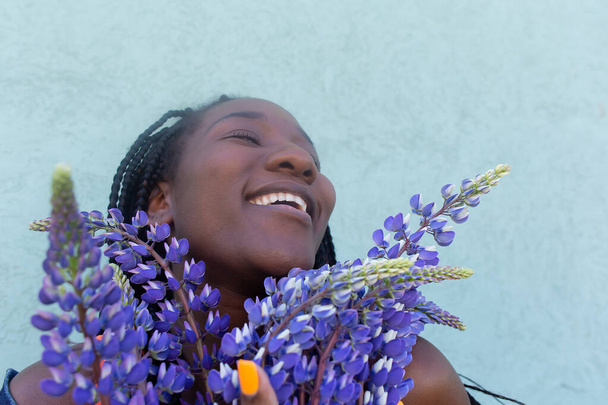 a boldog afro-amerikai nő szürke virágokkal - Fotó, kép