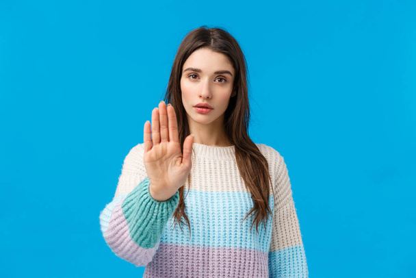 Please stop. Serious-looking assertive and confident young attractive woman pulling hand forward in prohibition, disapproval motion, show restriction telling enough, no sign, standing blue background - Photo, Image