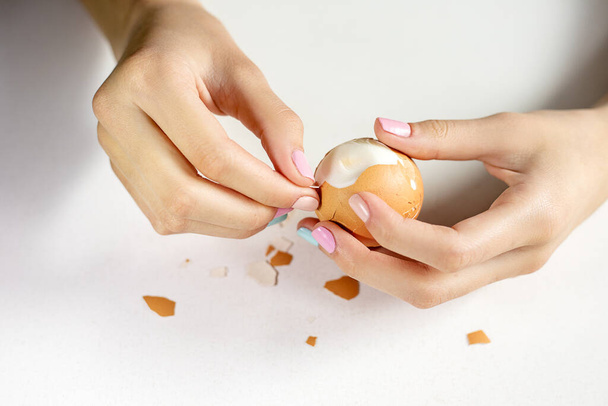 Fotos de hermosas manos de mujer elegantes con manicura que limpian un huevo hervido. Dieta Keto. Buena nutrición. Comida saludable. Granja
 - Foto, imagen