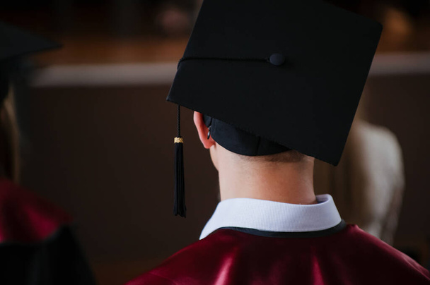 Young male student waiting during graduation ceremony with her celebration cap in focus and blurred background - Photo, Image