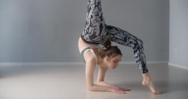 Aantrekkelijke jonge vrouw buigt voorover en voert verschillende yoga en gymnastische oefeningen op de vloer, persoon maakt fysieke training en stretching, yoga klassen 4k 120p Prores HQ 10 bit - Video