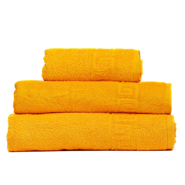 3フロントタオル黄色の色、寝室のタオル白の背景。白を基調としたカラフルな黄色のバスタオル。黄色いタオルを積め。パイル色のタオルは隔離します。同じ色の三つの綿タオル積層 - 写真・画像