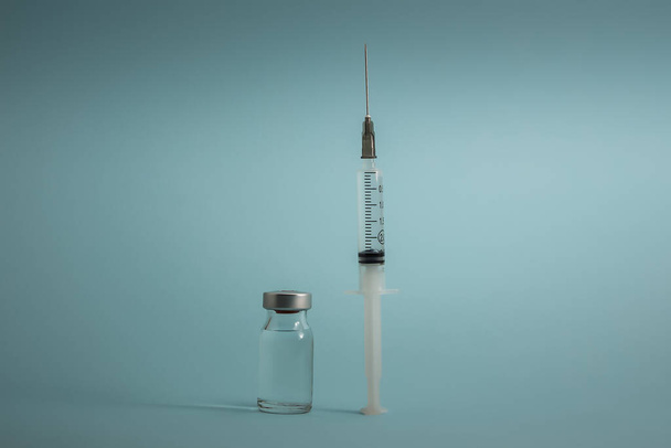 Kleine Impfflasche (Phiole) und Spritze isoliert auf blauem Hintergrund Impfung zur Vorbeugung, Immunisierung und Behandlung von Virus- und Bakterieninfektionen - Foto, Bild