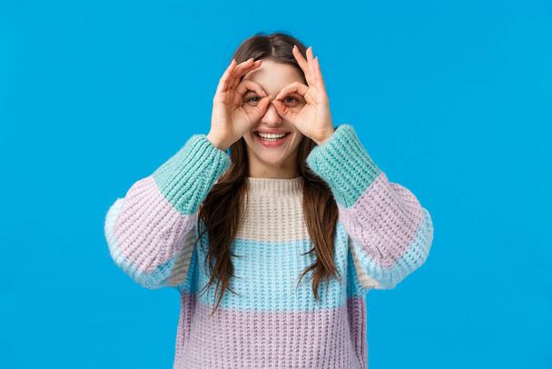 Girl searching for best shopping discounts, good offers. Good-looking charismatic woman in winter sweater, holding circles okay signs over eyes as if making glasses from fingers, smiling joyfully - Photo, Image