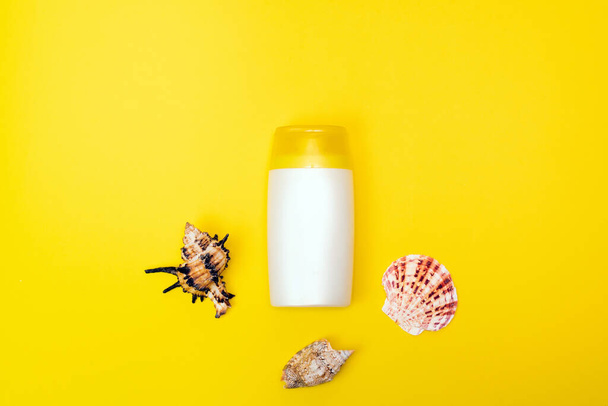 A suncream, shell are on the yellow background. Sun protection product. - Foto, Imagem