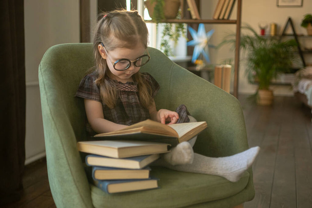 Little cute toddler girl in glasses reading books. back to school - Fotó, kép