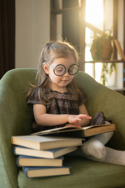Little cute toddler girl in glasses reading books. back to school - Fotoğraf, Görsel