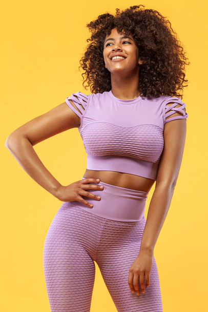 Lifestyle Concept. Portrait of beautiful happy and dancing African American woman with curly hair. Yellow studio background. Copy Space. - Foto, Bild