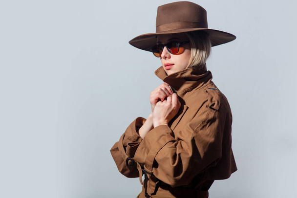 Style woman in cloak, hat and sunglasses on grey background  - Foto, afbeelding