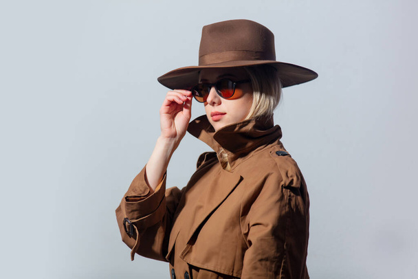Style woman in cloak, hat and sunglasses on grey background  - Фото, зображення